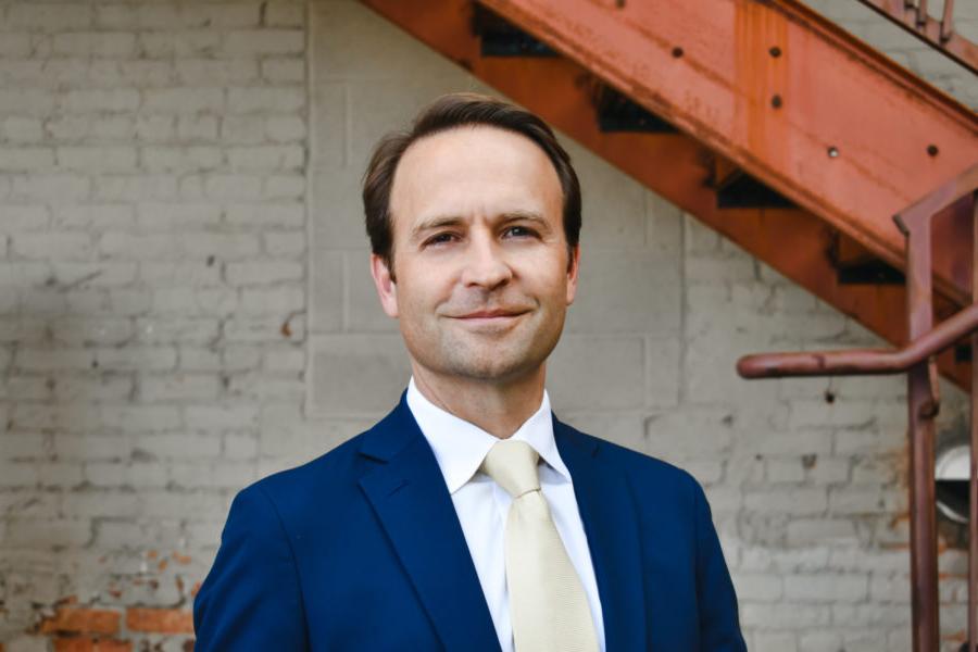 A man named Brian Calley poses in front of a building in Lansing